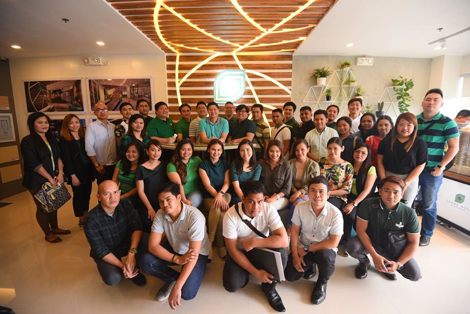 A group of people taking a photo in a well-designed interior, some seated in the front and others standing in the back.}